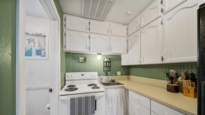 Una cocina con armarios blancos, una estufa y un fregadero.