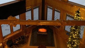 Una cabaña con ventanas amplias que dan a un paisaje nevado y un lago.