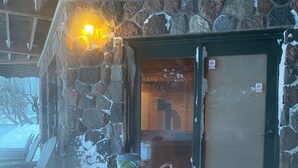 Un edificio de piedra con puerta de madera, un portavasos y un banco en el exterior.