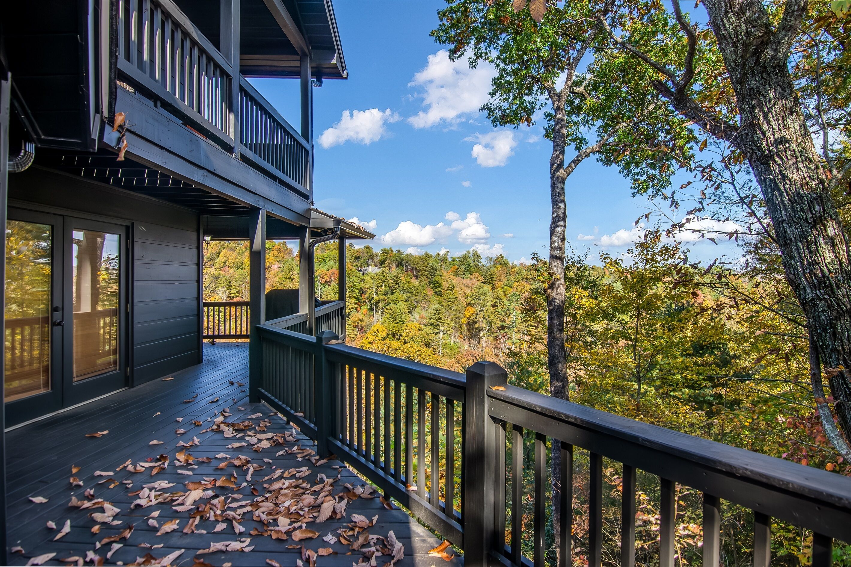 A two-story wooden building with a balcony overlooking a forested area.