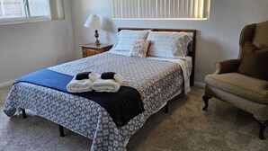 Una cama bien hecha con un edredón estampado, una almohada con una cita y un par de toallas dobladas sobre la cama.