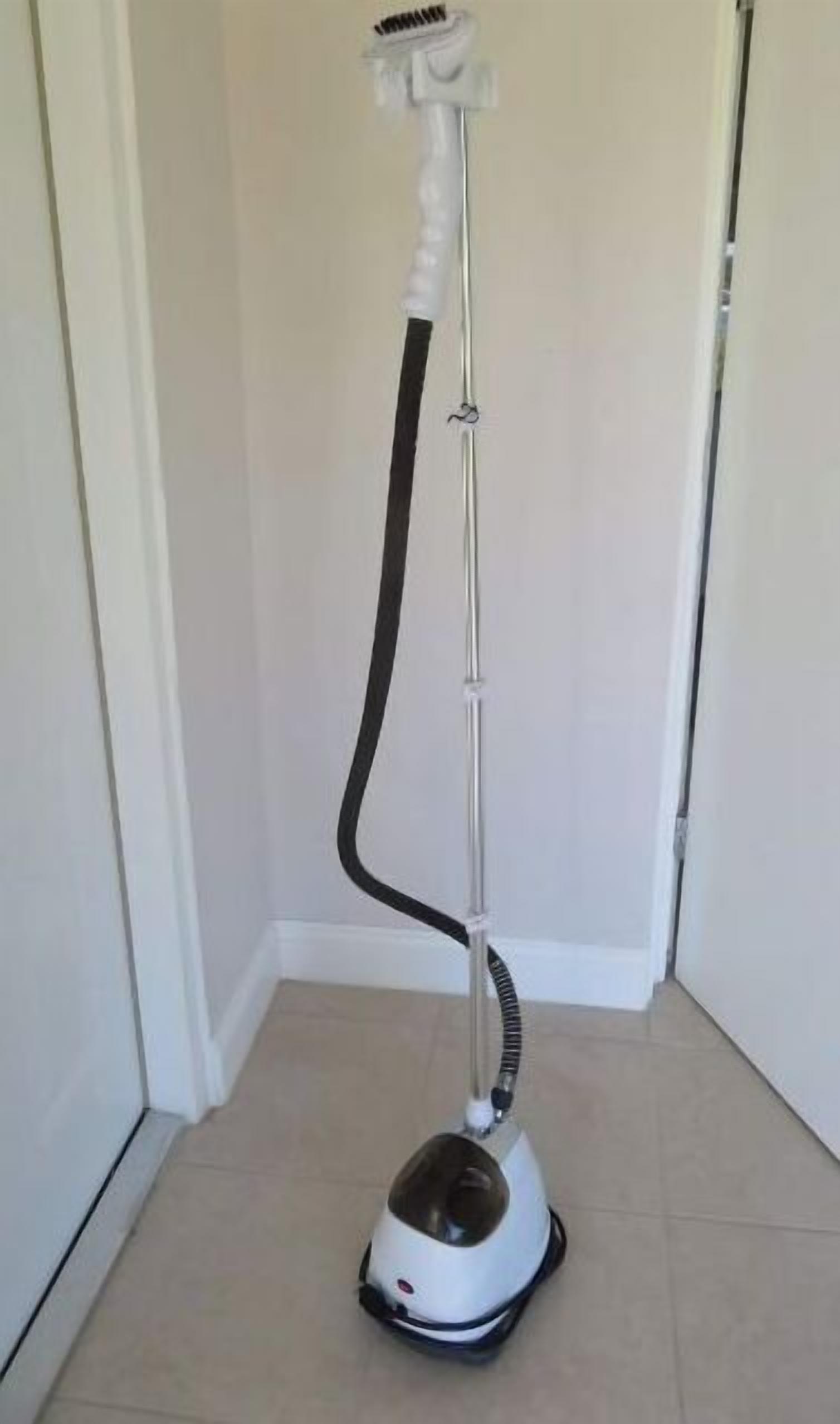 A standing vacuum cleaner in a hallway with white walls and a tiled floor.