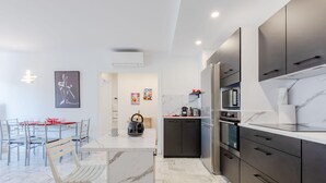 A modern kitchen with dark cabinets, a marble countertop, and a central island. - Renovated 3-Room Apartment in a Leafy Park (Cannes)
