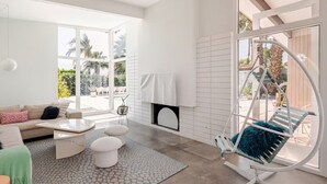 A modern living room with a sofa, coffee table, ottoman, and a hanging chair. - Mr. Pink's MCM Alexander with Pool, Hot Tub, Fire Pit (Palm Springs)