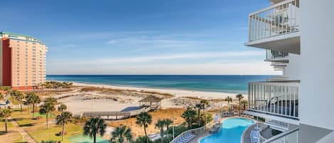 A hotel with a pool, beach view, and a high-rise building in the background.