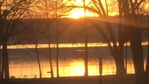 Auringonlasku, jossa aurinko on puiden ja aidan takana.