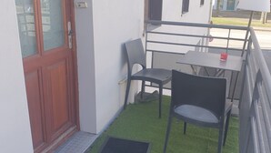 Un petit espace extérieur aménagé avec une table et des chaises, une porte et une fenêtre.