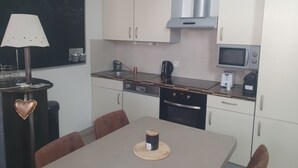 Une cuisine compacte avec des meubles blancs, un four à micro-ondes, une machine à café et un évier.