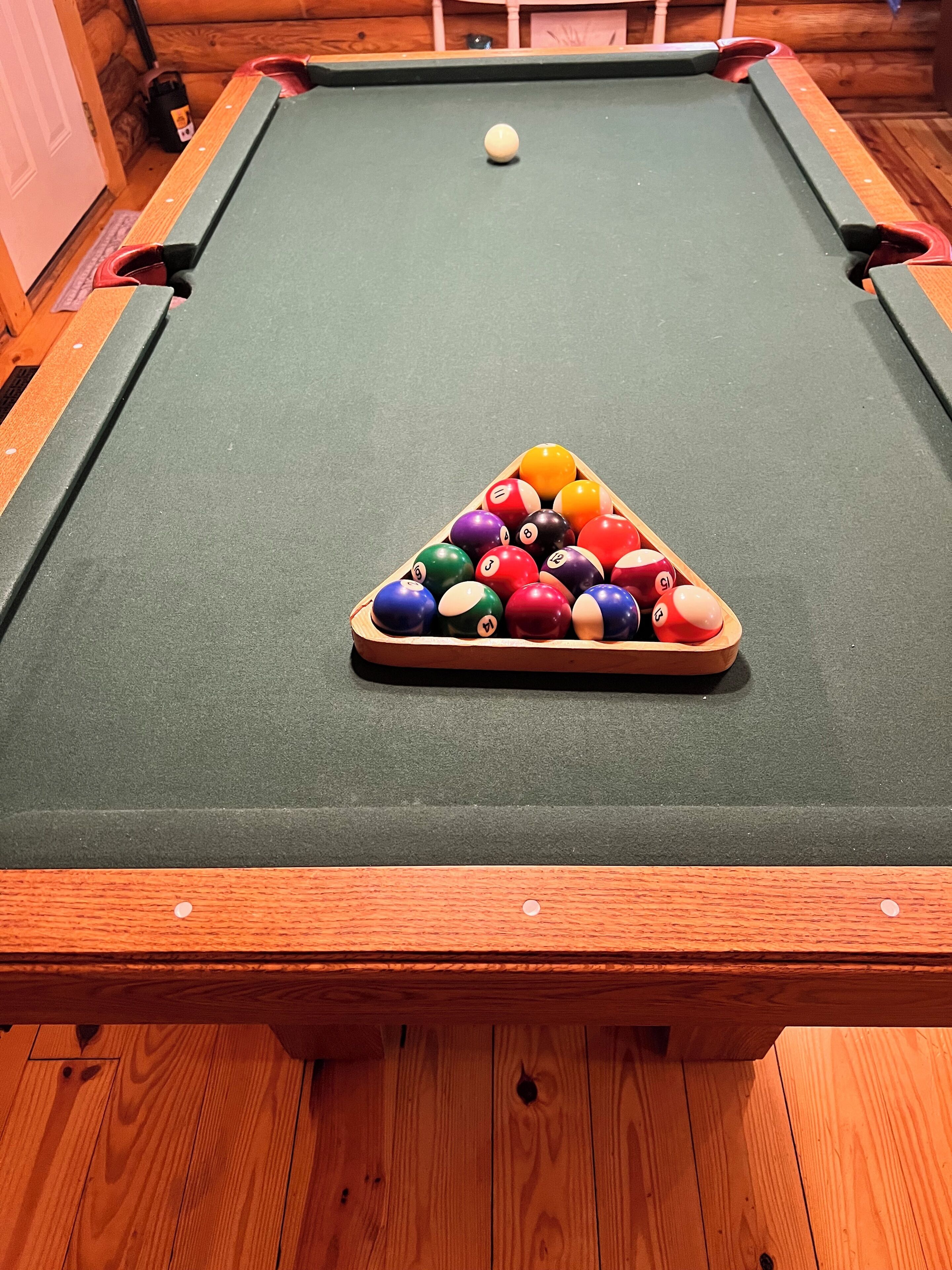 A pool table with a triangular rack of billiard balls and a cue ball.