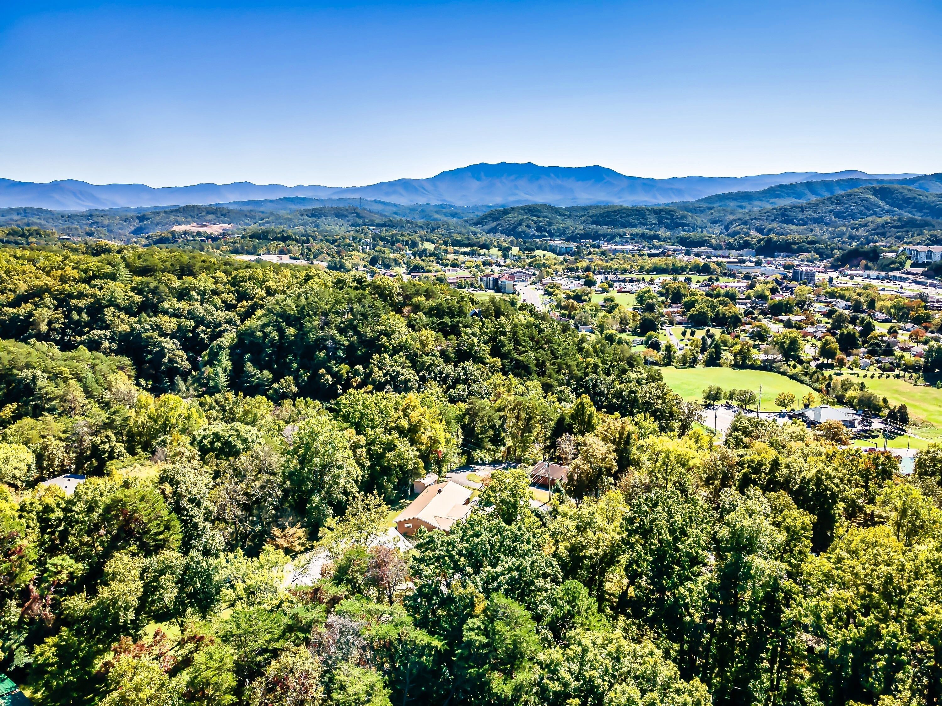 Une vue panoramique d’une ville entourée de forêts denses et de montagnes.