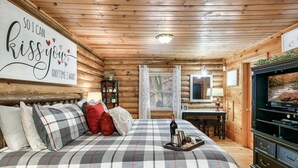Habitació acollidora d'una cabana de fusta amb un llit, una taula petita i una televisió.