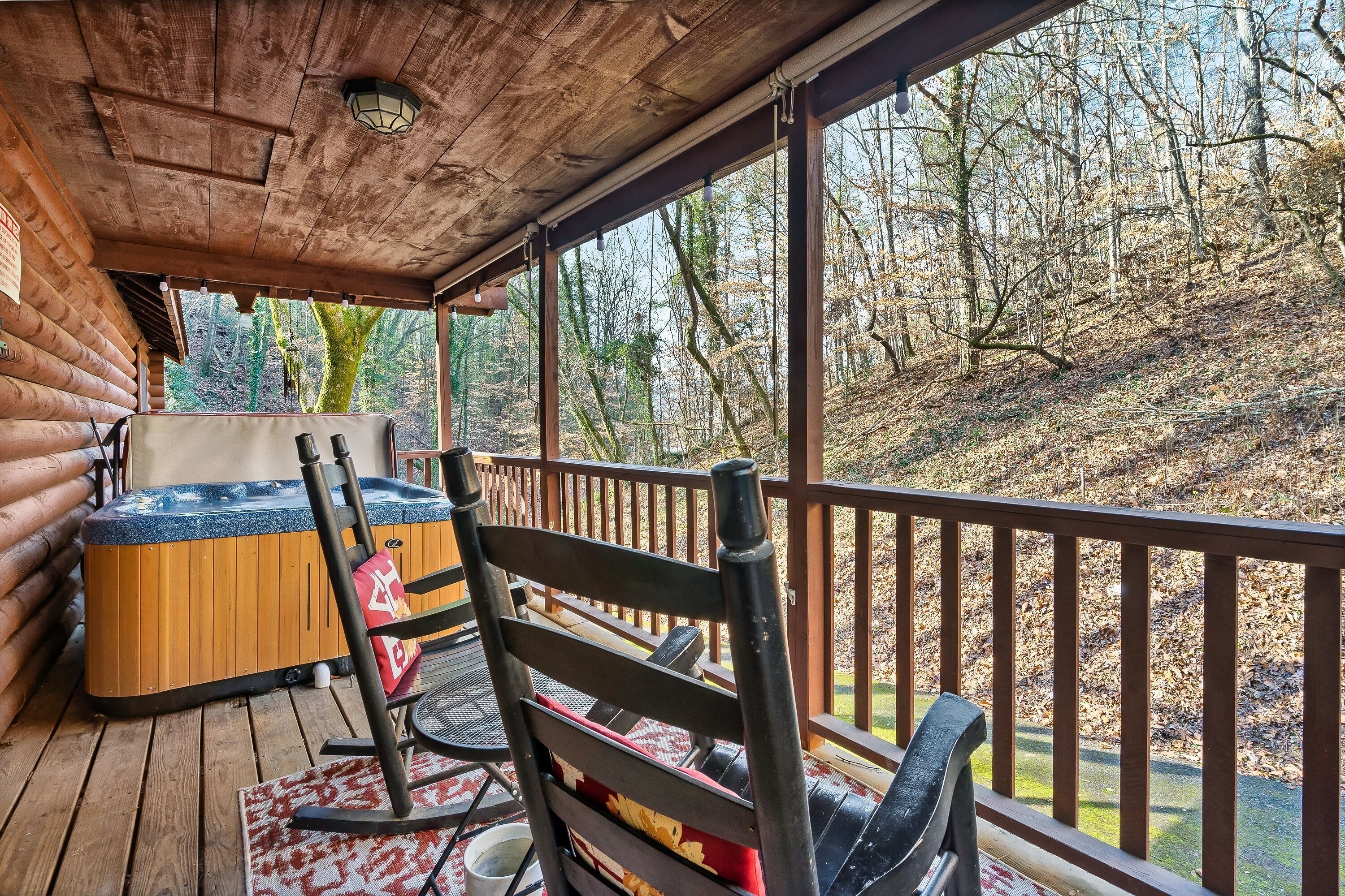 Una terraza de madera con un jacuzzi, una mecedora y una mesa con sillas.