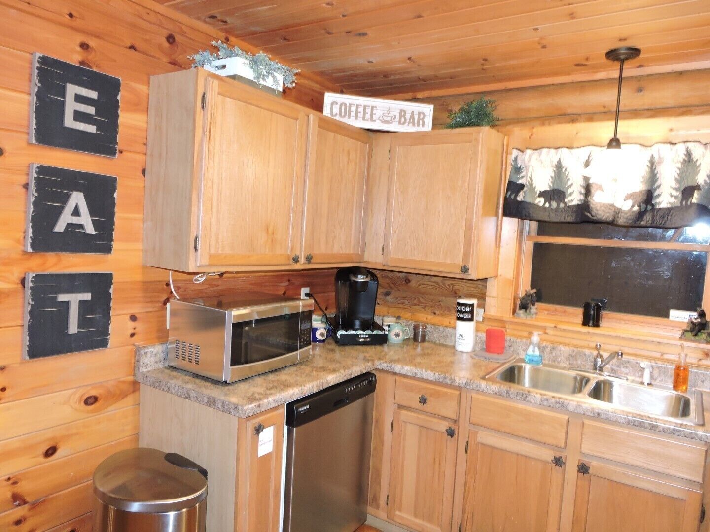 A compact kitchen with wooden cabinets, a microwave, a coffee maker, and a dishwasher.