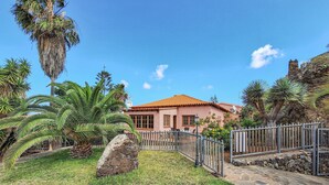 A building with a red-tiled roof, surrounded by palm trees and a stone wall. - 1 bedroom amazing apartment in Buenavista Del Norte (Buenavista Del Norte)