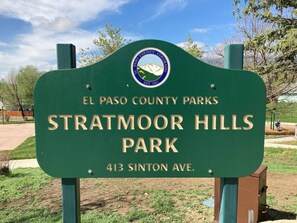 A green sign for Stratmoor Hills Park with the El Paso County Parks logo, located at 413 Sinton Ave. - 5BR Kid-friendly Retreat w/ Hot Tub, BBQ grill, Fire Pit, Near Attractions (Colorado Springs)
