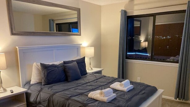 A neatly made bed with a dark quilt, two pillows, and two towels on the side. - 5BR Recently Updated Retreat w/ Hot Tub, BBQ grill, Fire Pit, Near Attractions (Colorado Springs)