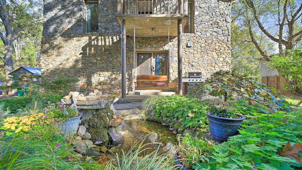 A stone house with a balcony, a small garden with a pond, and a barbecue area. - Eclectic Asheville Abode w/ Backyard Oasis! (Asheville)