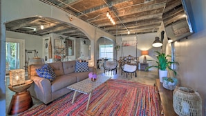 A spacious living area with a sofa, coffee table, and chairs, featuring exposed beams and a colorful rug. - Eclectic Asheville Abode w/ Backyard Oasis! (Asheville)