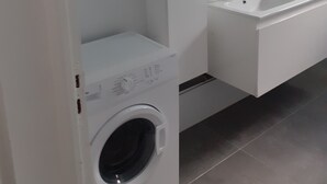 A modern bathroom with a built-in washing machine, a large mirror, and a dual sink vanity. - House terrace beach riviere (pointe noire)