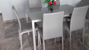 A dining area with a table and four chairs, a vase with flowers, and a laptop on the table. - House terrace beach riviere (pointe noire)