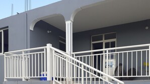 A two-story building with a white staircase and balcony railing. - House terrace beach riviere (pointe noire)