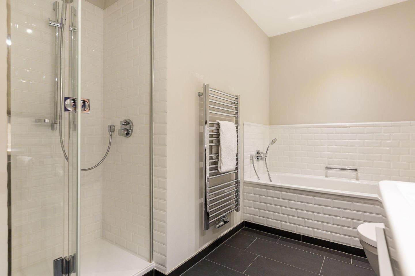 A modern bathroom with a glass-enclosed shower, a freestanding bathtub, and a towel rack.