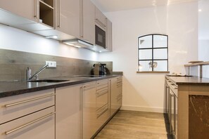 A modern kitchen with a built-in oven, stainless steel appliances, and a window with a grid design.