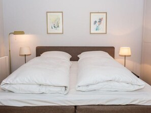 A neatly made bed with white linens and two pillows, flanked by two bedside lamps. - Villa Maybach, Whg. 1 Albert - Villa Maybach (Sylt)
