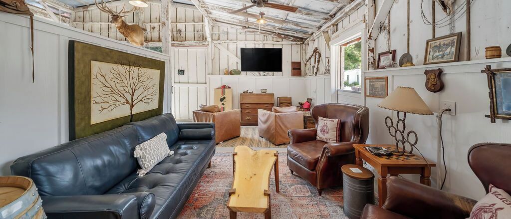 Un interno rustico con un divano in pelle, sedie di legno, un televisore e diverse decorazioni a parete.