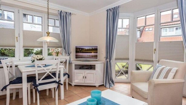 Una sala de estar acogedora con comedor, televisor y vistas al exterior.