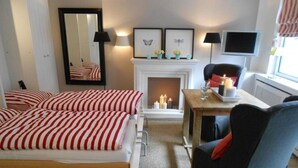 Une chambre d’hôtel avec un lit, une chaise, une cheminée et un téléviseur.