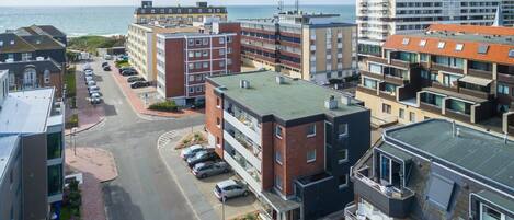 A coastal urban area with multi-story buildings, a parking lot, and a view of the sea.