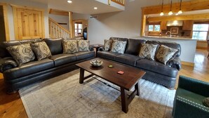 A spacious living room with a large sectional sofa, a wooden coffee table, and a staircase leading to an upper level.