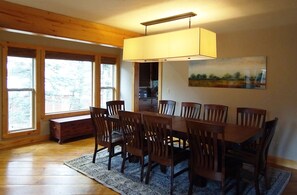 Une salle à manger avec une table et des chaises en bois, un banc et une grande fenêtre.