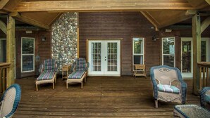 A covered porch with wicker furniture and a stone wall.