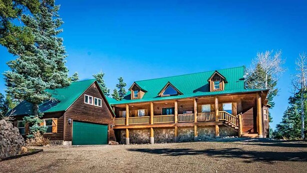 A large wooden lodge with a green roof, multiple balconies, and a stone foundation.