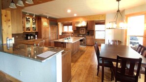 A spacious kitchen with wooden cabinets, a large island, and a dining area with a table and chairs.
