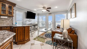 A spacious kitchen with wooden cabinets, a marble countertop, and a dining area with a glass table and chairs. - Galveston  2/2 Gulf Front -  Heated Pool, 2 Hot Tubs, W/D in Unit (Galveston)