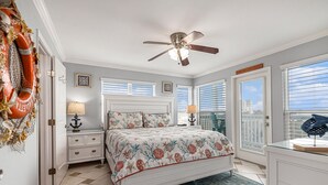 A bedroom with a bed, nightstands, a ceiling fan, and a view through the window. - Galveston  2/2 Gulf Front -  Heated Pool, 2 Hot Tubs, W/D in Unit (Galveston)