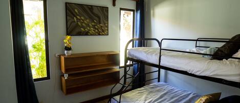 A room with two bunk beds, a ceiling fan, a window with curtains, a wall-mounted air conditioner, and a shelf with a plant.