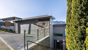 Un bâtiment moderne avec une façade en pierre, un garage et un escalier menant à une porte.