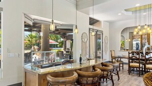 A modern kitchen with a large island, bar stools, pendant lighting, and a view of the outdoor patio. - Saguaro Estate - .3 Acre Private Paradise (La Quinta)