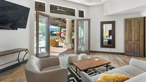 A modern living room with a flat-screen TV, a sofa, a coffee table, and a large mirror. - Saguaro Estate - .3 Acre Private Paradise (La Quinta)