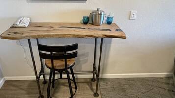 A small wooden table with a metal frame, a black chair, and a phone on the table.