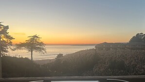 Ein Tisch mit zwei Stühlen auf einem Balkon mit Blick auf einen Sonnenuntergang.