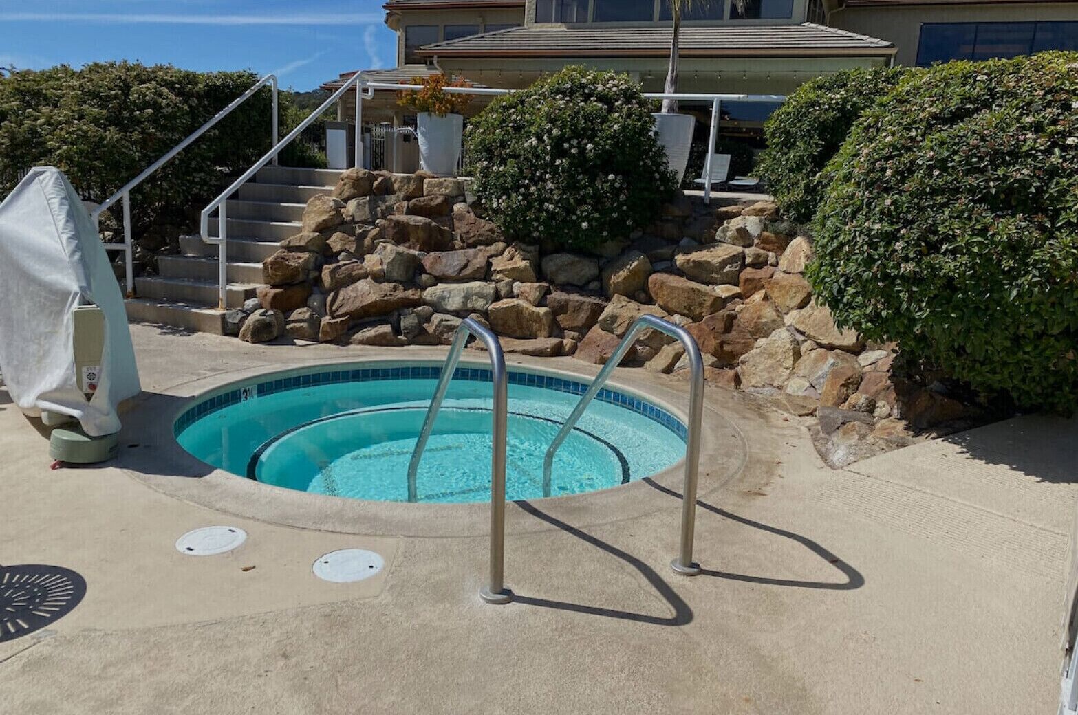 Une piscine avec un mur en pierre et un escalier menant à un bâtiment.