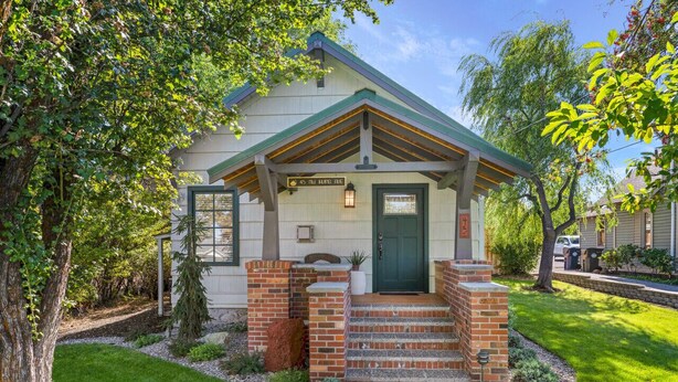 A single-story house with a green door, a small porch, and a brick entrance. - Downtown Craftsman with King Bed and Private Yard - Walk Everywhere  (Bend)