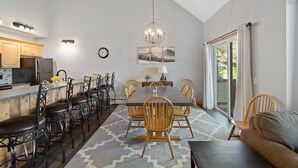 Una cocina moderna con comedor, que presenta una isla grande, sillas de madera y una araña.