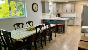Uma cozinha moderna com armários brancos, uma mesa de jantar de madeira e cadeiras.