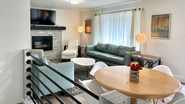 Uma sala de estar moderna com lareira, sofá, mesa de jantar e escada.
